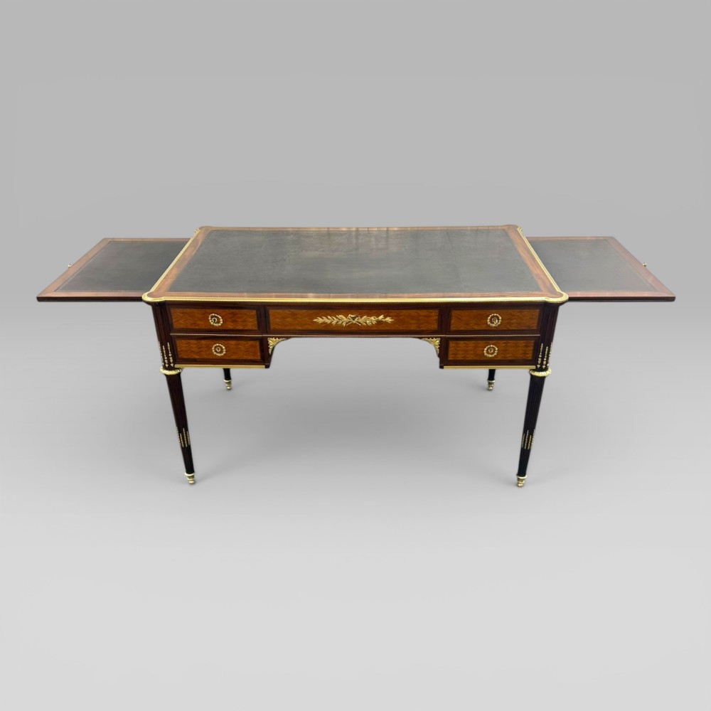 A Louis XVI style mahogany and parquetry writing desk featuring a dark leather top, gilt-bronze mounts, five drawers, and fluted tapered legs. View III