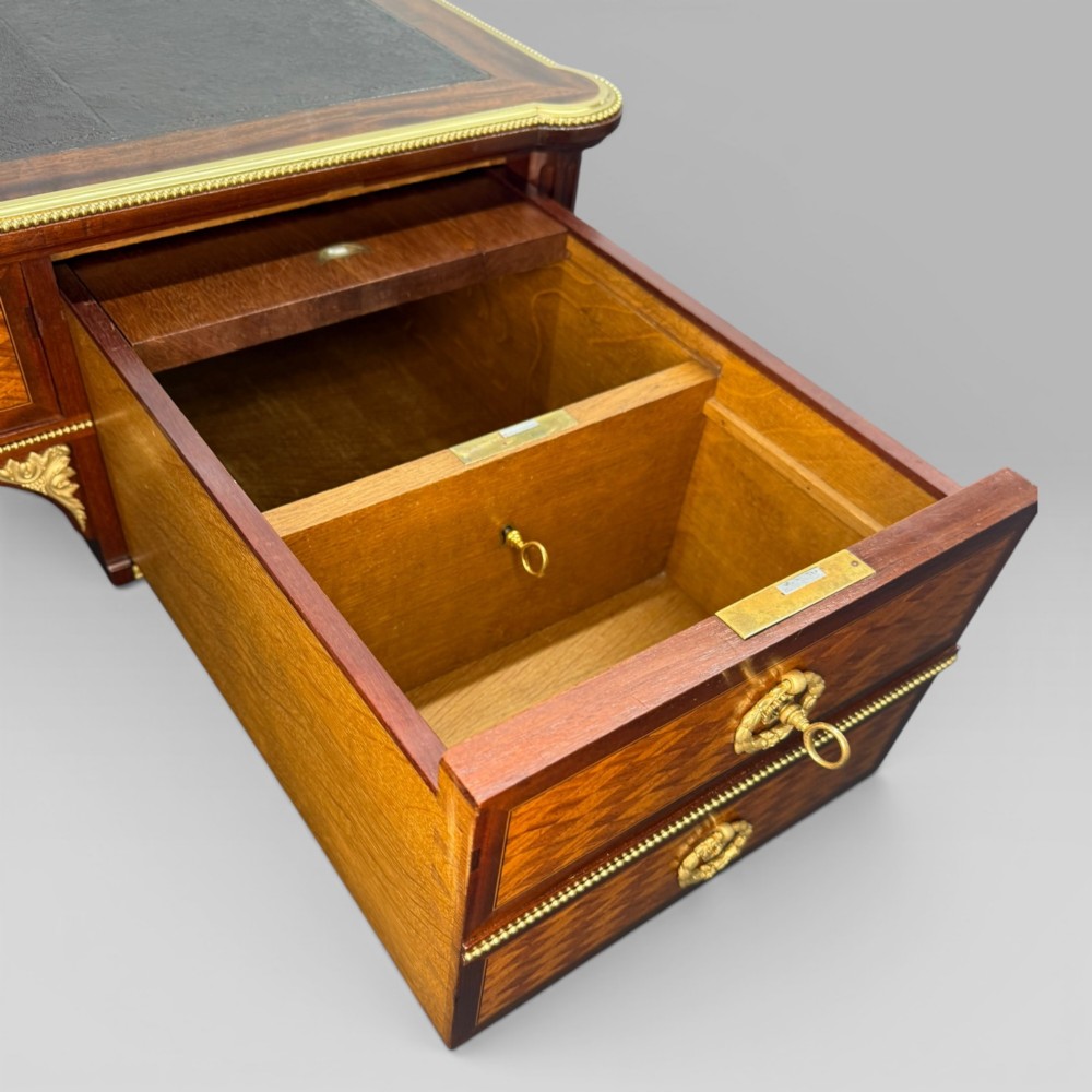 A Louis XVI style mahogany and parquetry writing desk featuring a dark leather top, gilt-bronze mounts, five drawers, and fluted tapered legs. View XI