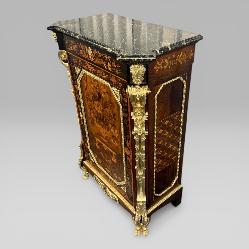 A nineteenth-century dark wood pier cabinet featuring detailed floral marquetry, polished gilt-bronze mounts, classical mask figures, and a black marble top. View IV