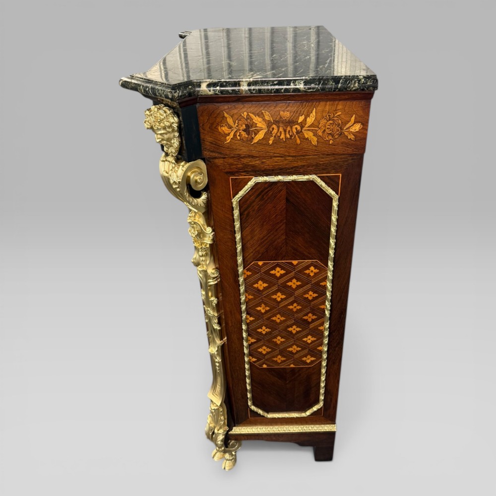 A nineteenth-century dark wood pier cabinet featuring detailed floral marquetry, polished gilt-bronze mounts, classical mask figures, and a black marble top. View VII