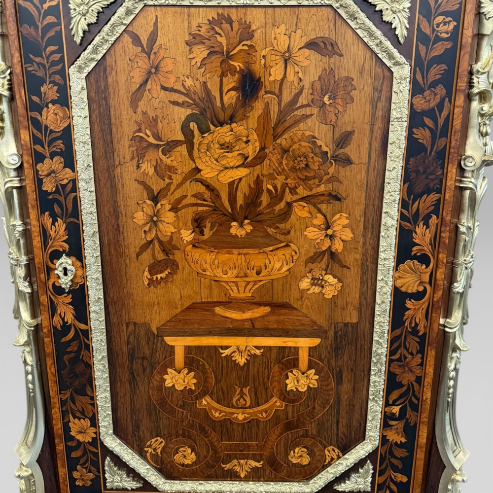 A nineteenth-century dark wood pier cabinet featuring detailed floral marquetry, polished gilt-bronze mounts, classical mask figures, and a black marble top. View VIII