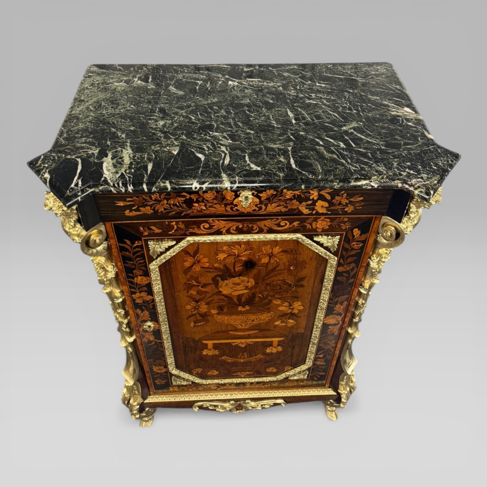 A nineteenth-century dark wood pier cabinet featuring detailed floral marquetry, polished gilt-bronze mounts, classical mask figures, and a black marble top. View X