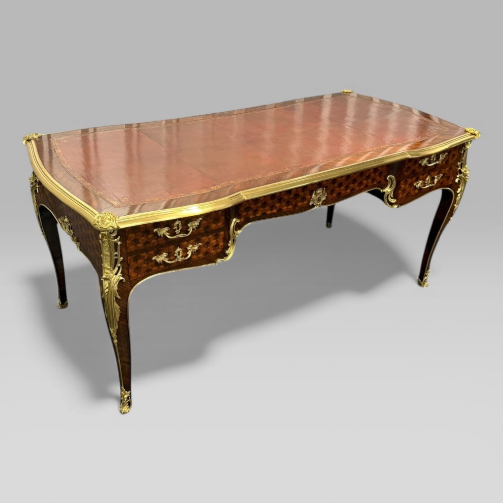 A late nineteenth-century French kingwood bureau plat featuring parquetry veneers, gilt bronze ormolu mounts, cabriole legs, and a brown leather inset writing surface.