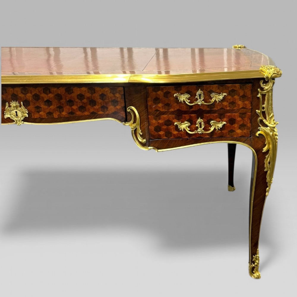 A late nineteenth-century French kingwood bureau plat featuring parquetry veneers, gilt bronze ormolu mounts, cabriole legs, and a brown leather inset writing surface. View V