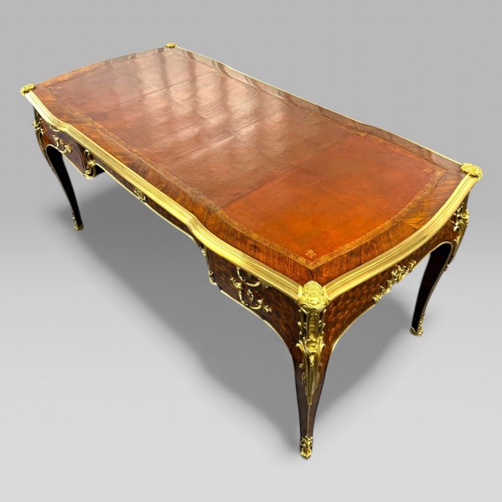 A late nineteenth-century French kingwood bureau plat featuring parquetry veneers, gilt bronze ormolu mounts, cabriole legs, and a brown leather inset writing surface. View X
