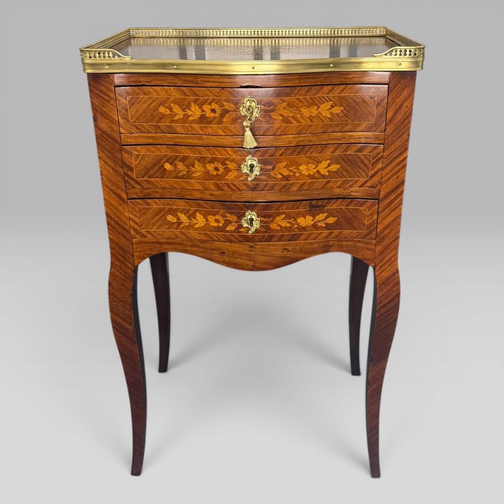 A French Louis XV style kingwood petite commode featuring three floral marquetry drawers, cabriole legs, and a brass gallery top. View II