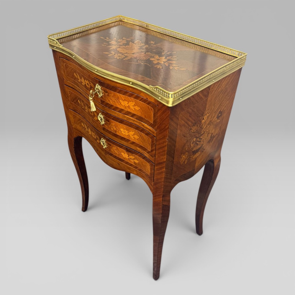 A French Louis XV style kingwood petite commode featuring three floral marquetry drawers, cabriole legs, and a brass gallery top. View III