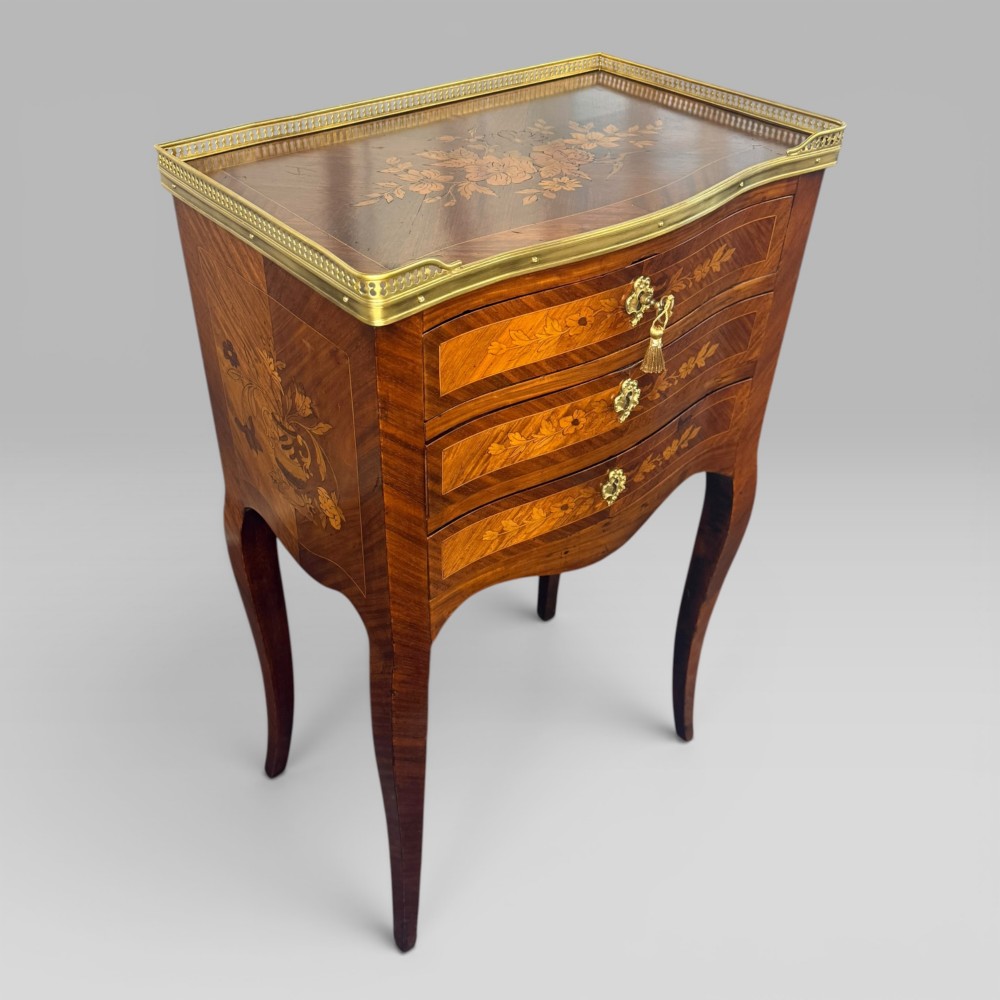 A French Louis XV style kingwood petite commode featuring three floral marquetry drawers, cabriole legs, and a brass gallery top. View IV