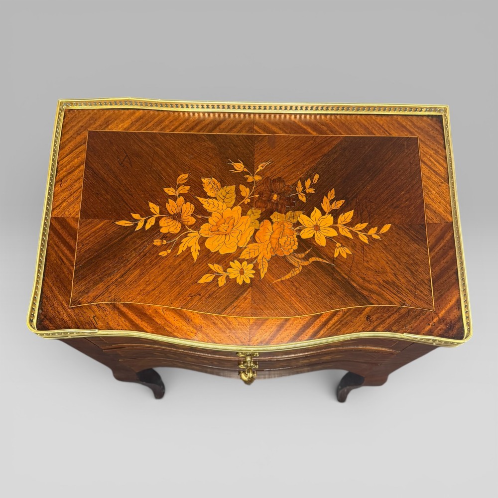 A French Louis XV style kingwood petite commode featuring three floral marquetry drawers, cabriole legs, and a brass gallery top. View V