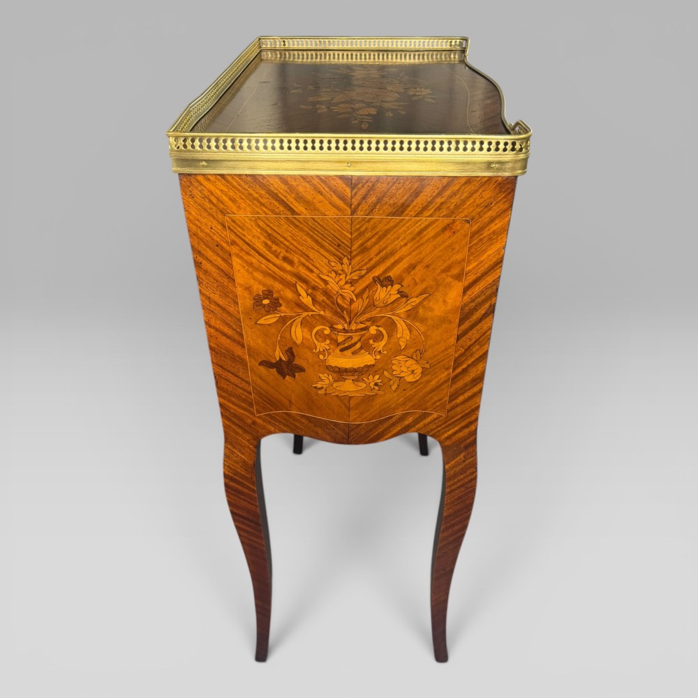 A French Louis XV style kingwood petite commode featuring three floral marquetry drawers, cabriole legs, and a brass gallery top. View VI