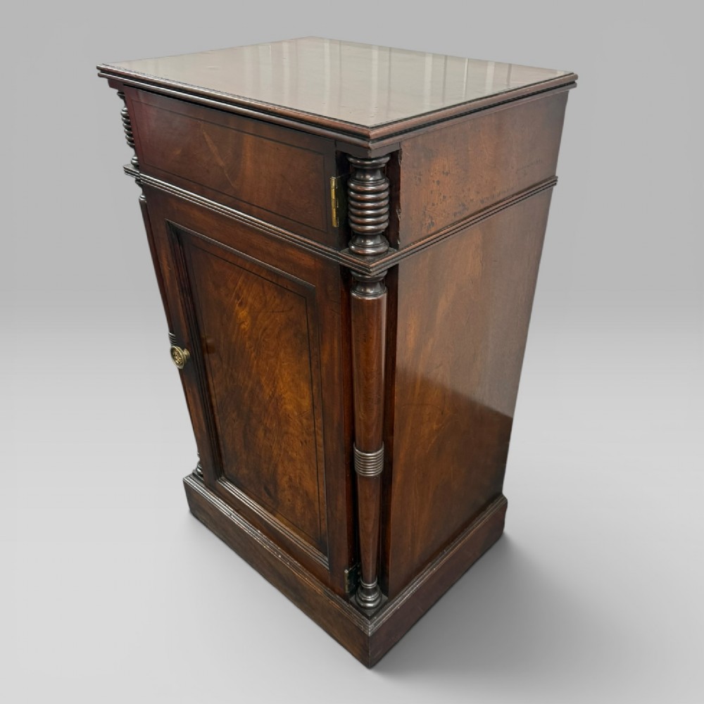 A Regency mahogany cellarette cabinet featuring reeded corner columns, a panelled door, and a flat top surface. View VI