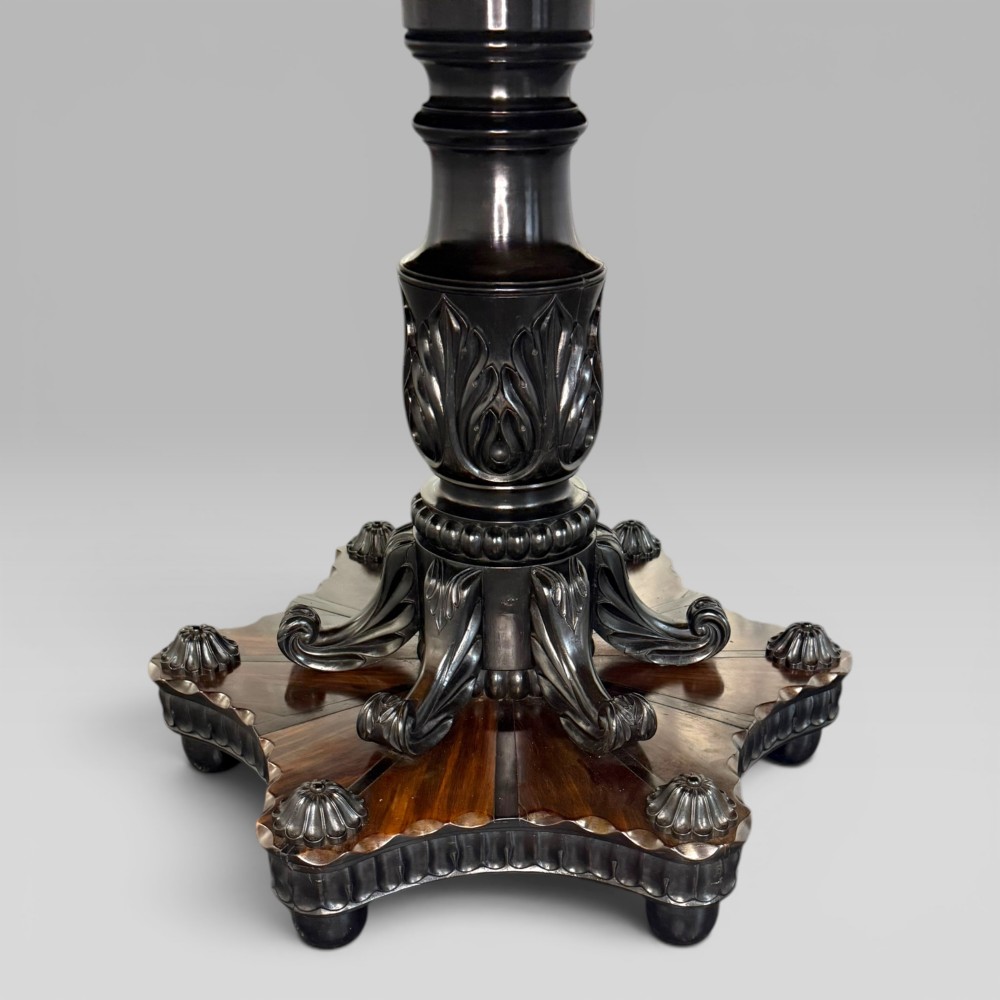 Overhead view of a circular centre table top showing radiating calamander wood veneers, light stringing, a central star motif, and a carved ebony border. View III