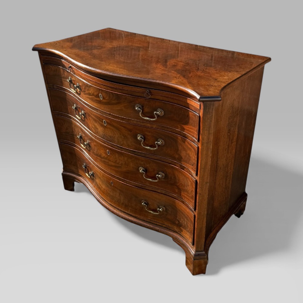 An 18th-century Georgian mahogany chest of drawers featuring a curved serpentine front, four graduated drawers, brass swan-neck handles, and a pull-out brushing slide. View III