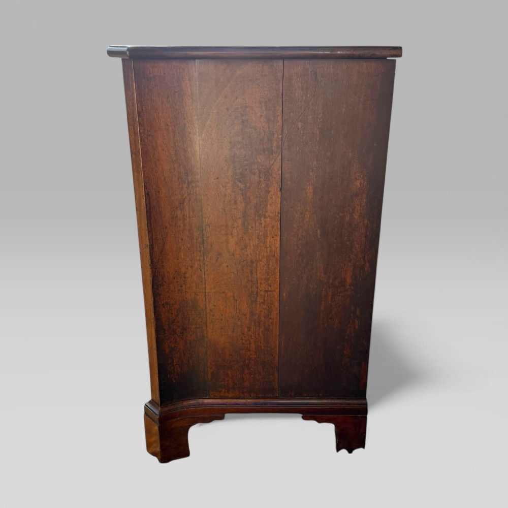 An 18th-century Georgian mahogany chest of drawers featuring a curved serpentine front, four graduated drawers, brass swan-neck handles, and a pull-out brushing slide. View XI