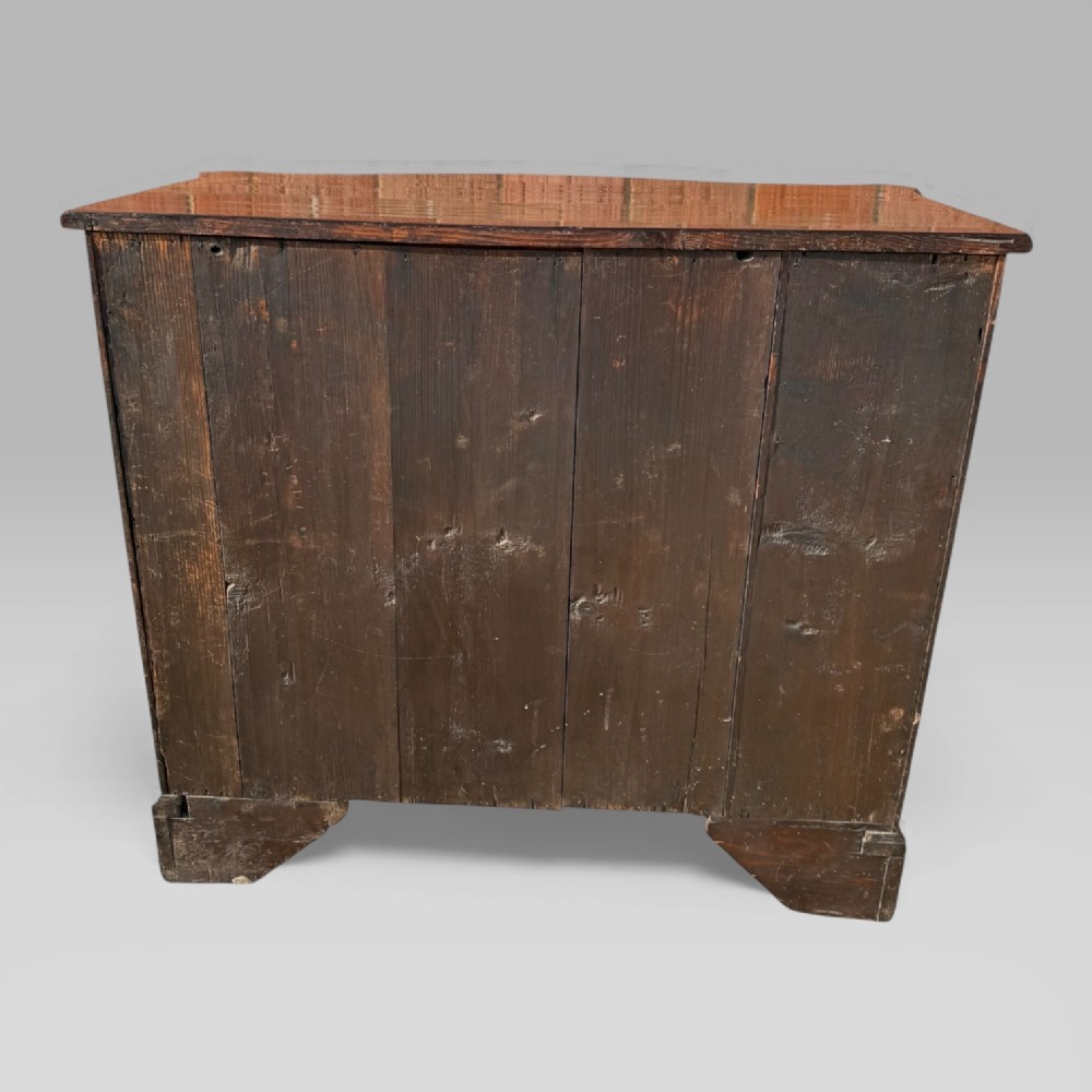 An 18th-century Georgian mahogany chest of drawers featuring a curved serpentine front, four graduated drawers, brass swan-neck handles, and a pull-out brushing slide. View XV