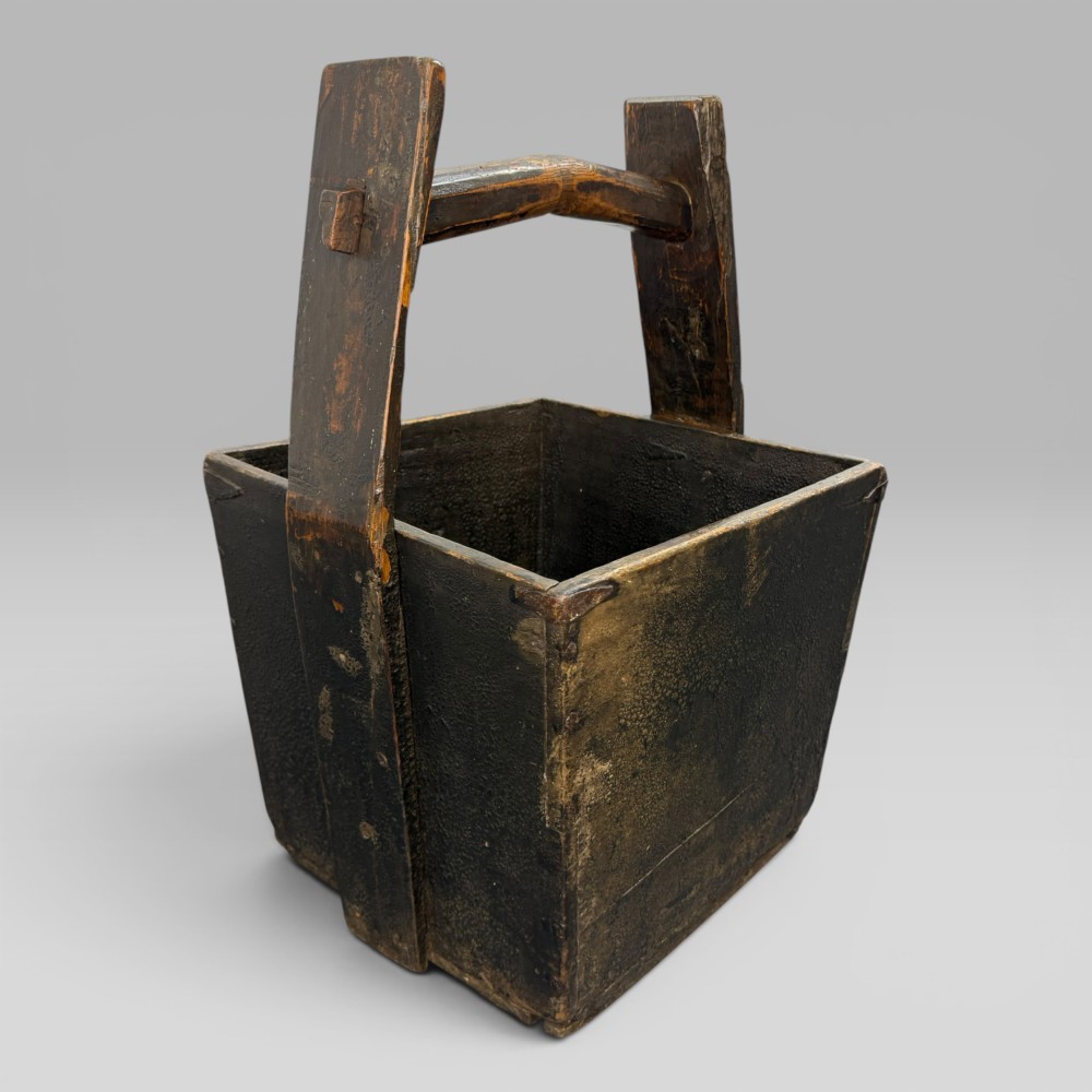 An antique dark brown Chinese elm harvest bucket featuring a tapered square body and a high wooden carrying handle with mortise and tenon joinery. View III