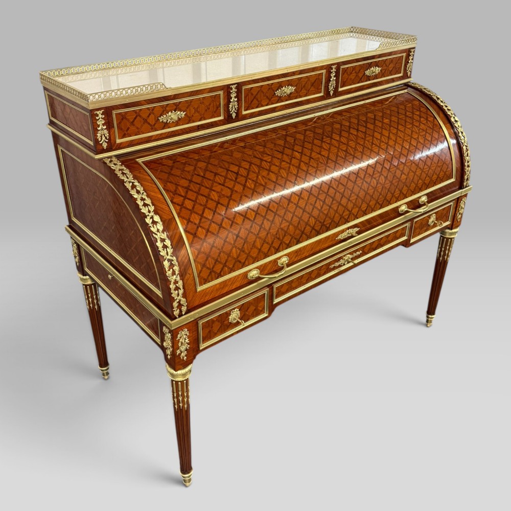 A French Louis XVI style cylinder desk featuring detailed geometric diamond parquetry, gilded bronze mounts, a top brass gallery rail, and slender fluted legs. View III