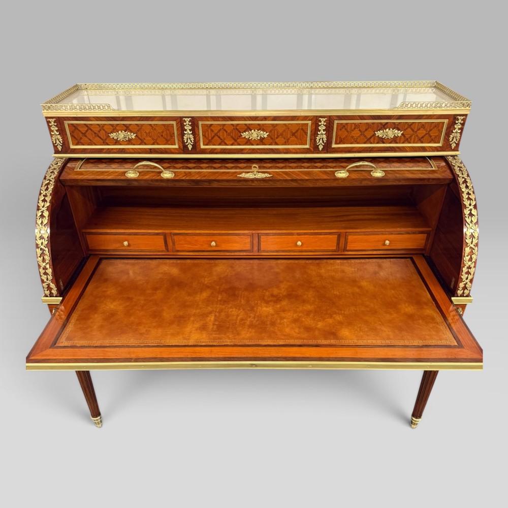 A French Louis XVI style cylinder desk featuring detailed geometric diamond parquetry, gilded bronze mounts, a top brass gallery rail, and slender fluted legs. View VII