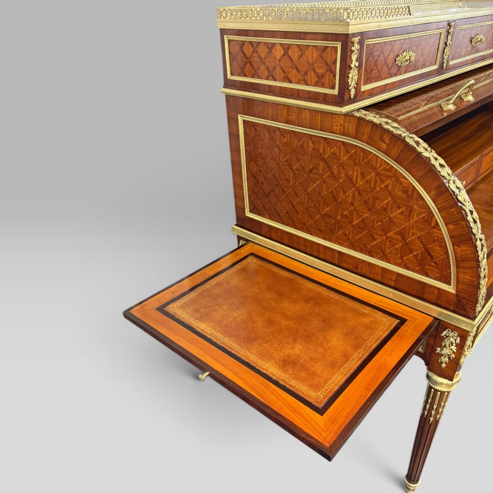 A French Louis XVI style cylinder desk featuring detailed geometric diamond parquetry, gilded bronze mounts, a top brass gallery rail, and slender fluted legs. View IX