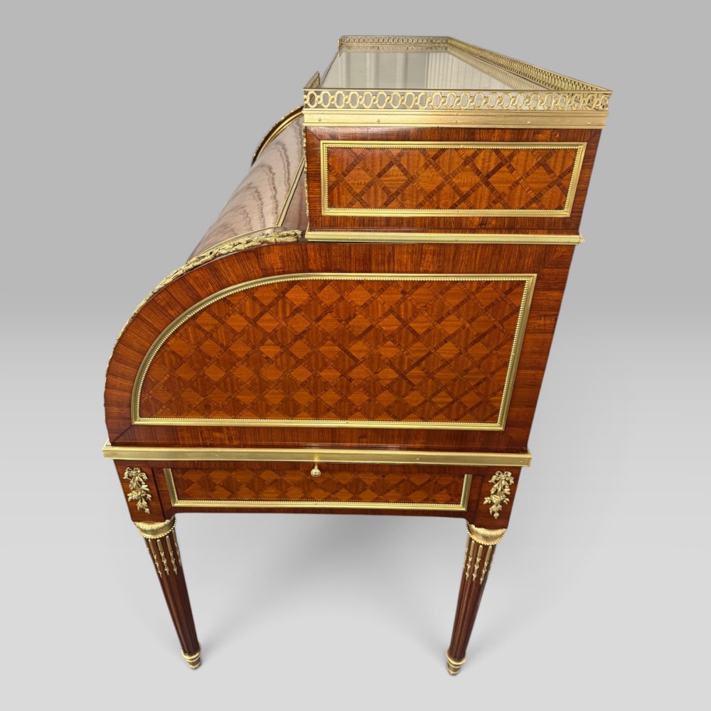 A French Louis XVI style cylinder desk featuring detailed geometric diamond parquetry, gilded bronze mounts, a top brass gallery rail, and slender fluted legs. View XII