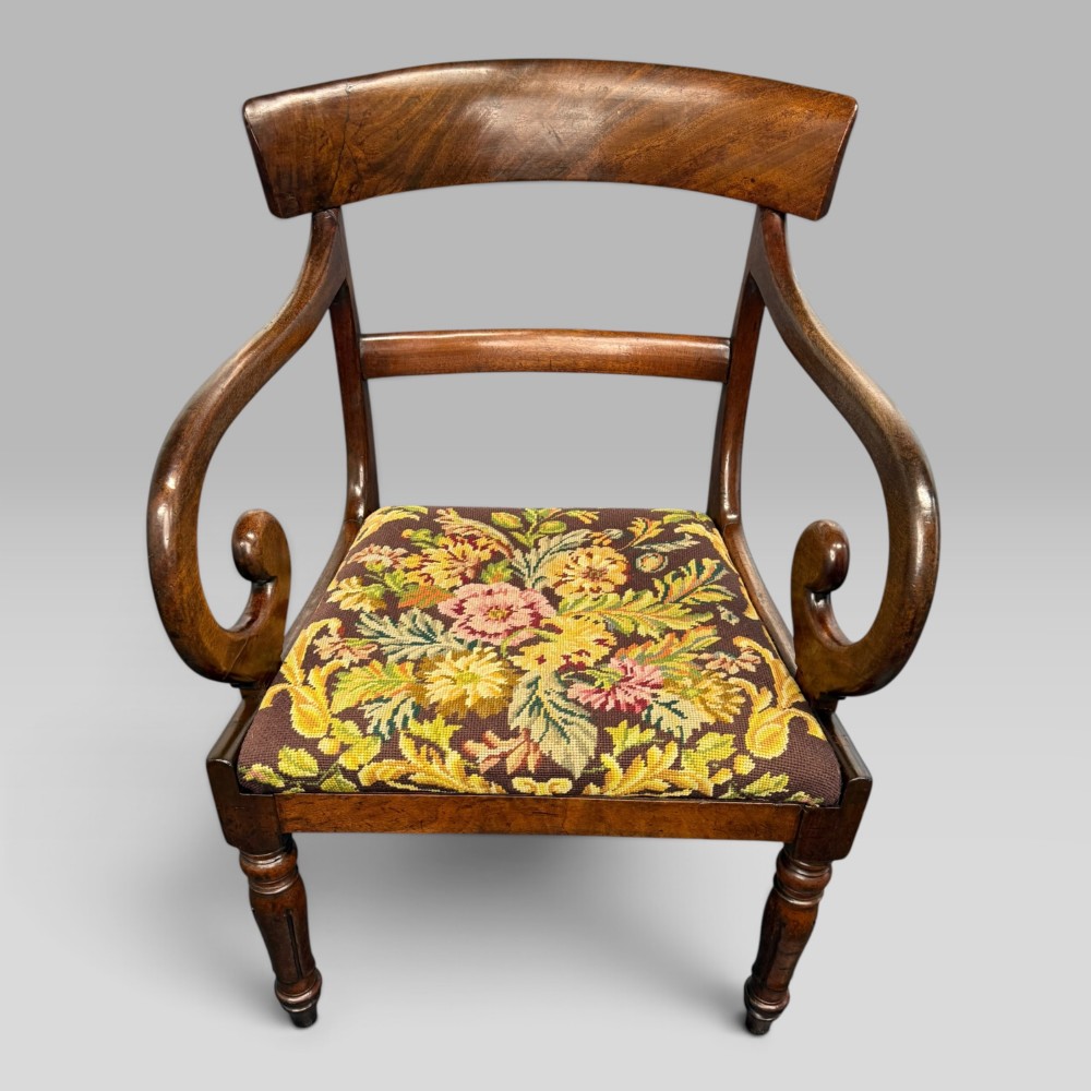 An antique William IV mahogany elbow armchair featuring scrolled armrests, turned front legs, and a floral tapestry upholstered seat. View II