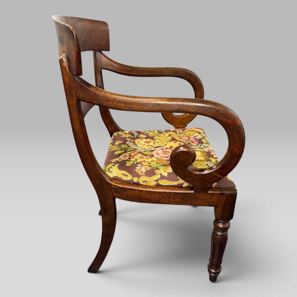 An antique William IV mahogany elbow armchair featuring scrolled armrests, turned front legs, and a floral tapestry upholstered seat. View V