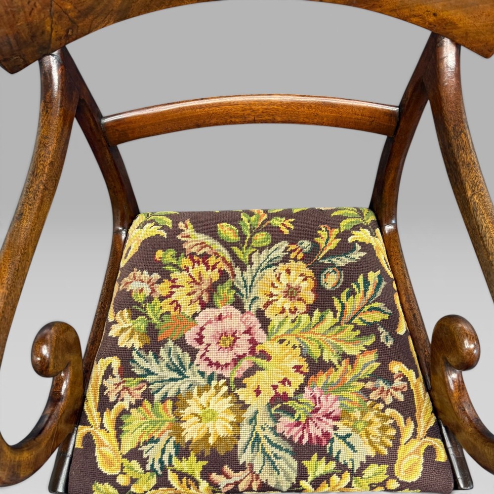 An antique William IV mahogany elbow armchair featuring scrolled armrests, turned front legs, and a floral tapestry upholstered seat. View VI