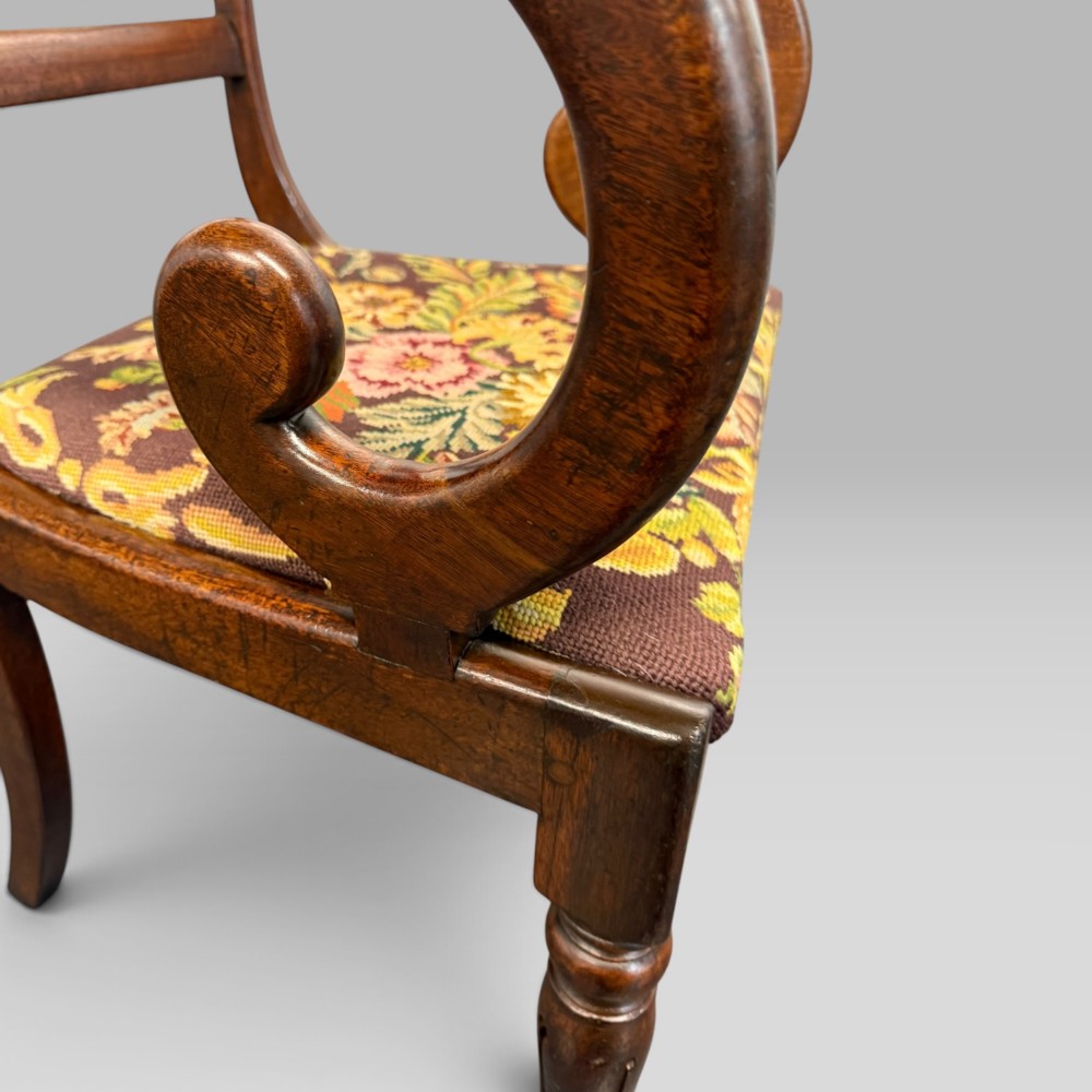 An antique William IV mahogany elbow armchair featuring scrolled armrests, turned front legs, and a floral tapestry upholstered seat. View VIII