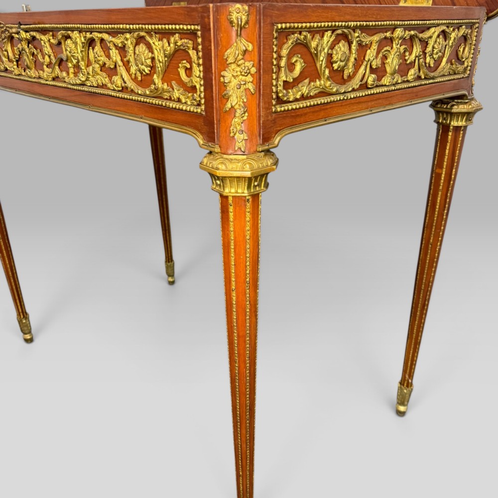 A rectangular French Louis XVI style bijouterie display table featuring a glazed glass top, decorative gilt bronze mounts along the frieze, and slender tapered legs ending in brass sabots. View X