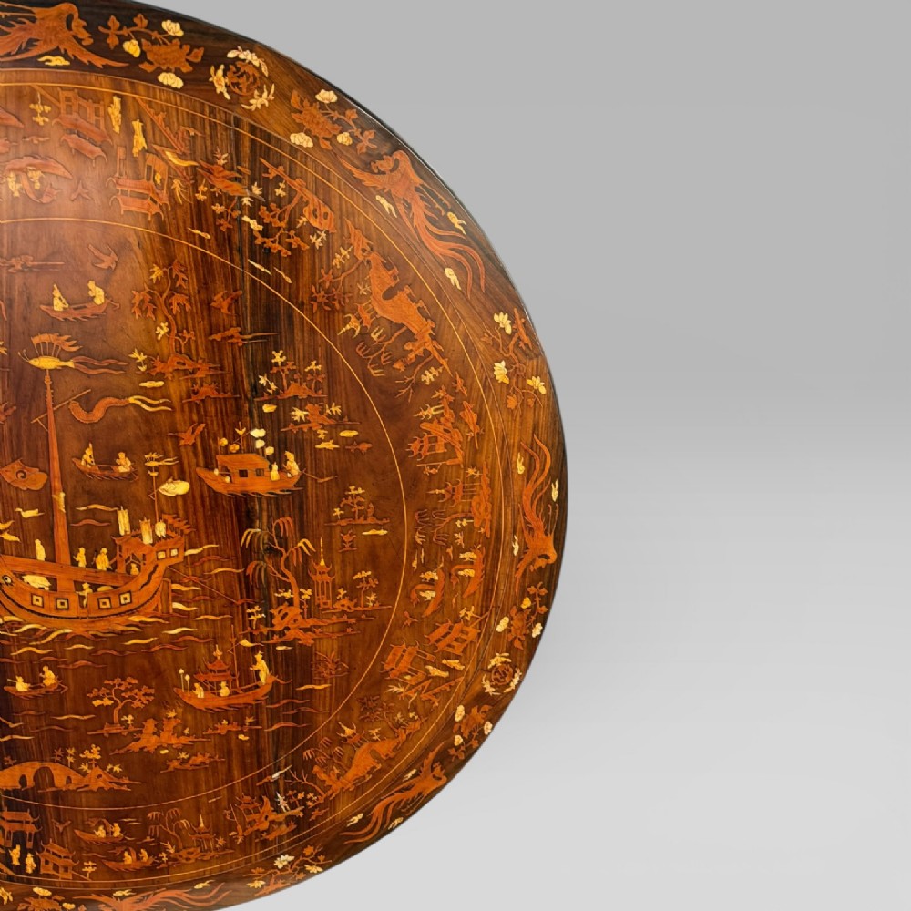 A circular dark rosewood centre table featuring detailed marquetry inlays depicting ships, pagodas, and flora. View VI