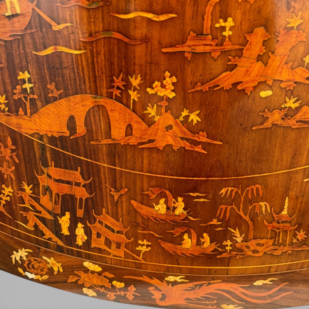 A circular dark rosewood centre table featuring detailed marquetry inlays depicting ships, pagodas, and flora. View XIII