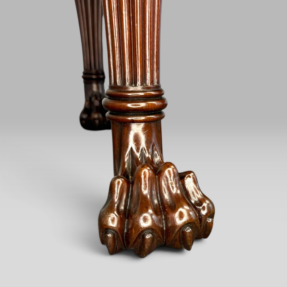 An antique Regency flame mahogany sideboard featuring a breakfront top, reeded columns, brass ring handles, and six carved lion paw feet. View X