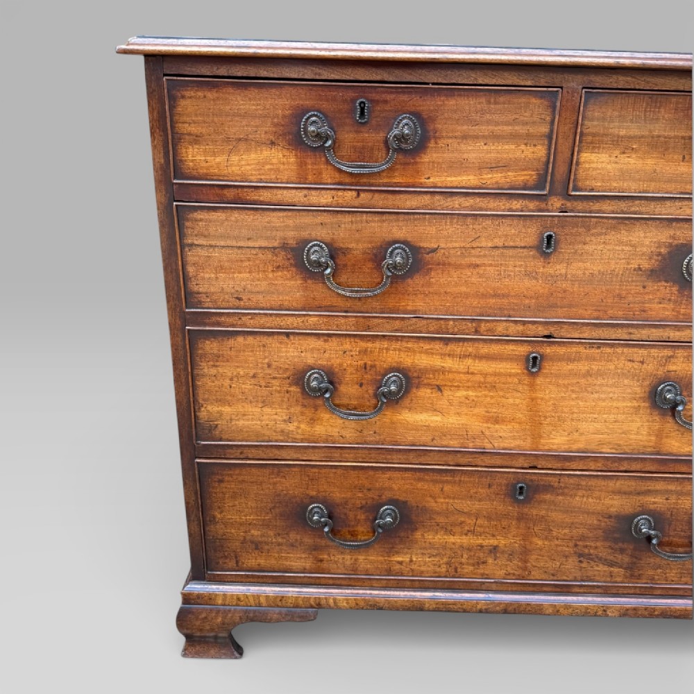 An antique George III mahogany chest of drawers featuring a two-over-three drawer layout, brass swan-neck handles, keyhole escutcheons, and bracket feet. View V