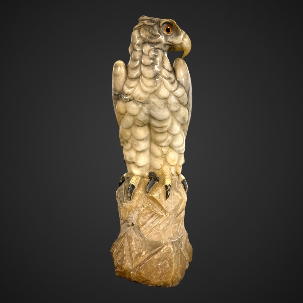 A 19th-century carved off-white Carrara marble sculpture depicting an eagle with inset amber glass eyes perched on a rock. View XII