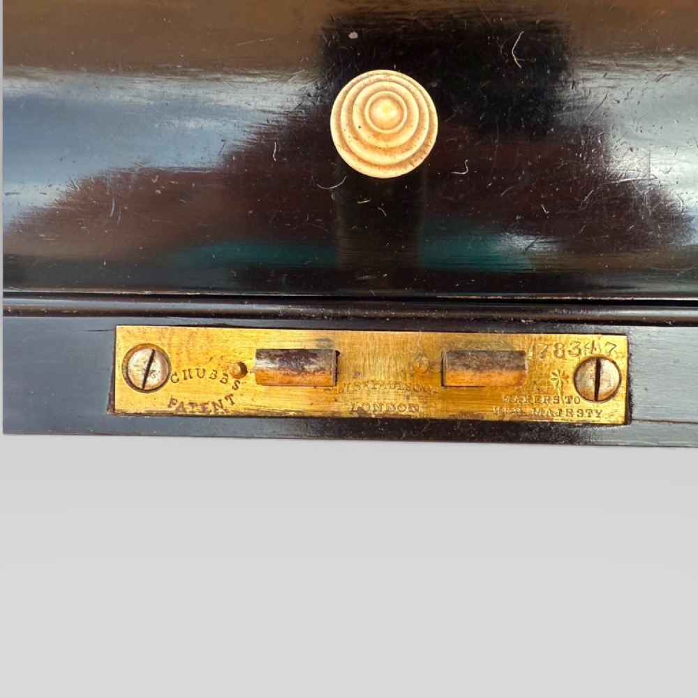 A rectangular mahogany and rosewood writing slope featuring brass bound edges, foliate brass inlay borders, a keyhole escutcheon, and an engraved brass cartouche. View XI