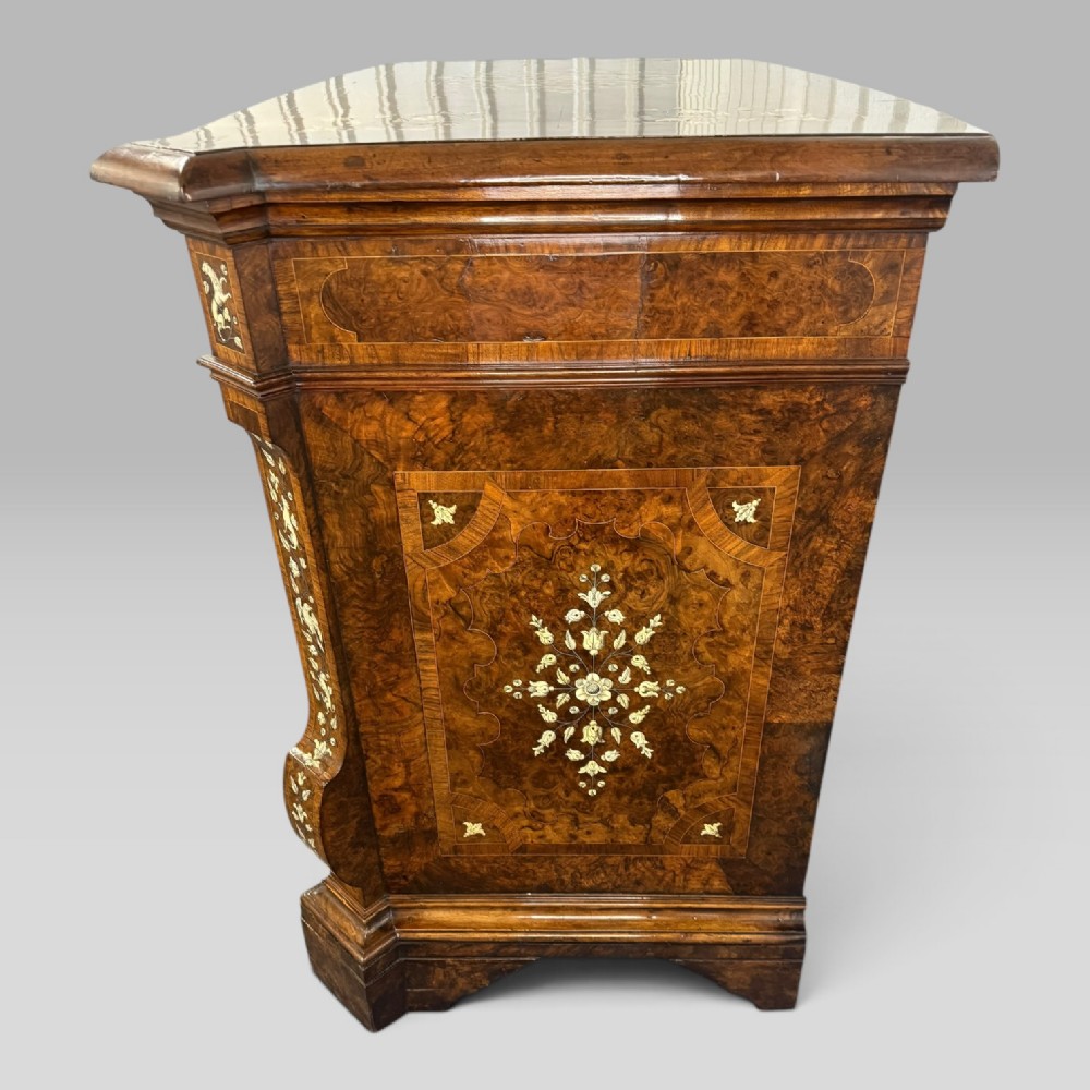 An Italian Baroque walnut commode featuring floral bone inlays across six drawer fronts, side panels, and top surface, supported by bracket feet. View VI