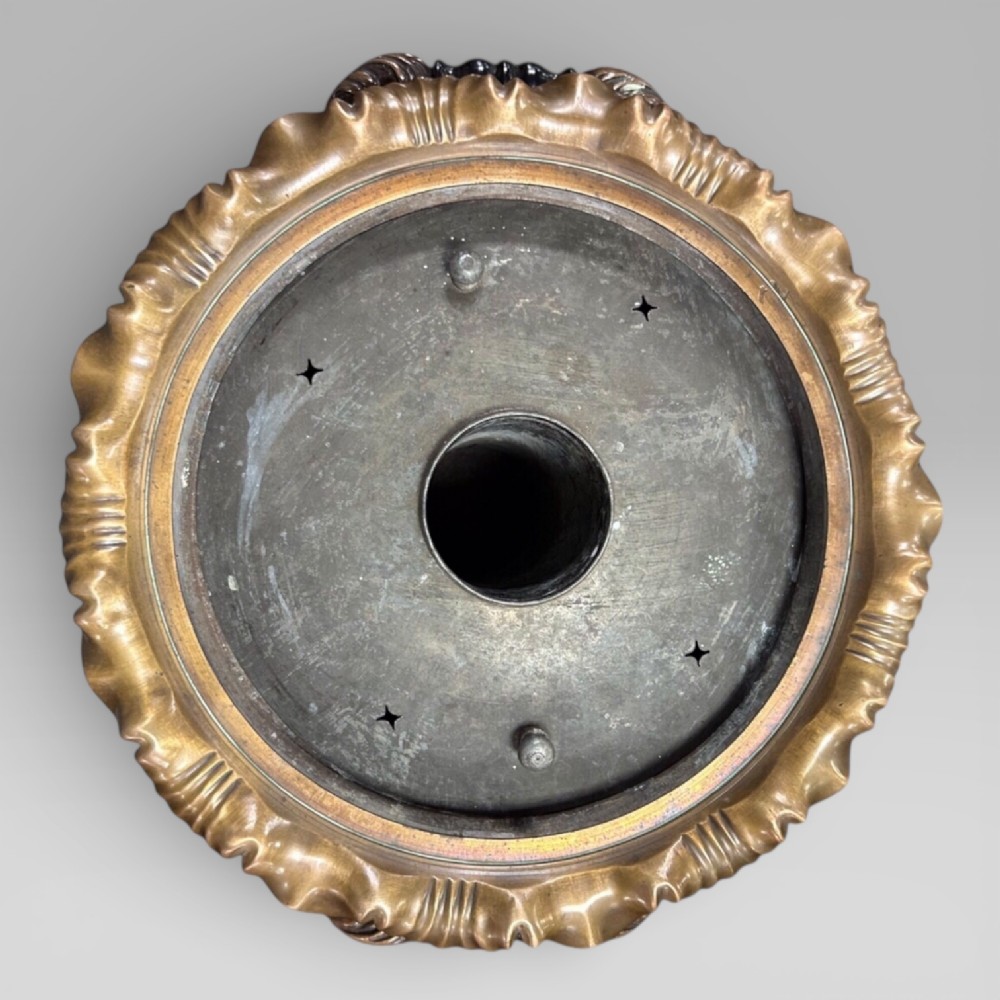 Top-down view of an antique Victorian copper samovar showing a crimped outer rim and a central heating pipe surrounded by a perforated metal interior.