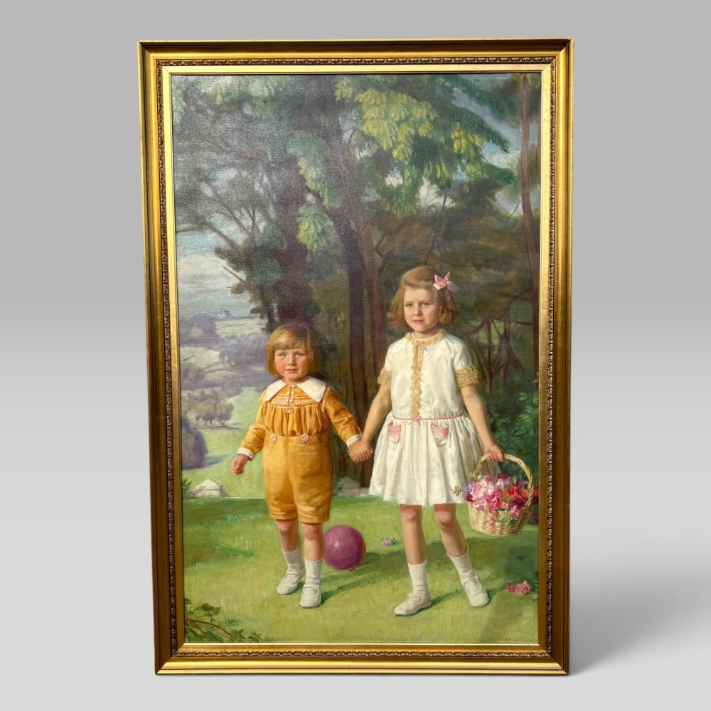 A full-length 1920s oil painting depicting two young children in a landscape setting, housed within a gilded wooden frame.