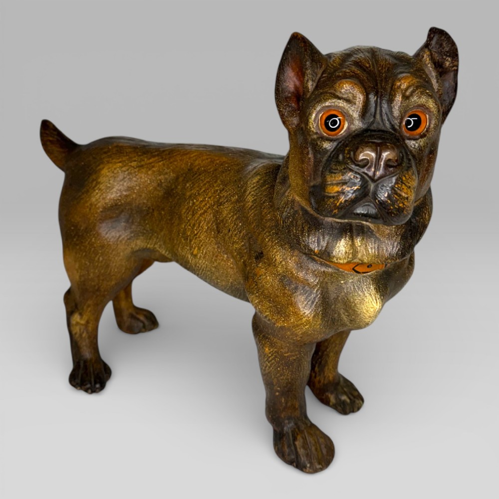 A dark brown painted terracotta dog sculpture standing upright with glass eyes and a moulded collar.