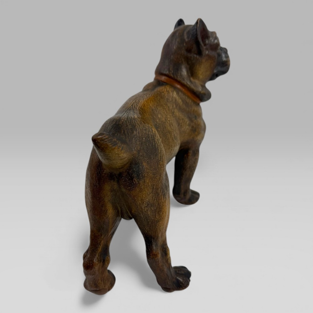 A dark brown painted terracotta dog sculpture standing upright with glass eyes and a moulded collar. View VI