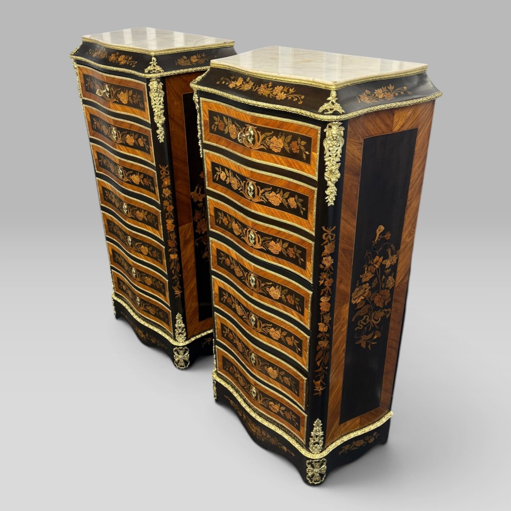 A pair of French Napoleon III narrow serpentine chests in kingwood and tulipwood featuring floral marquetry, gilt-bronze mounts, and marble tops. View II