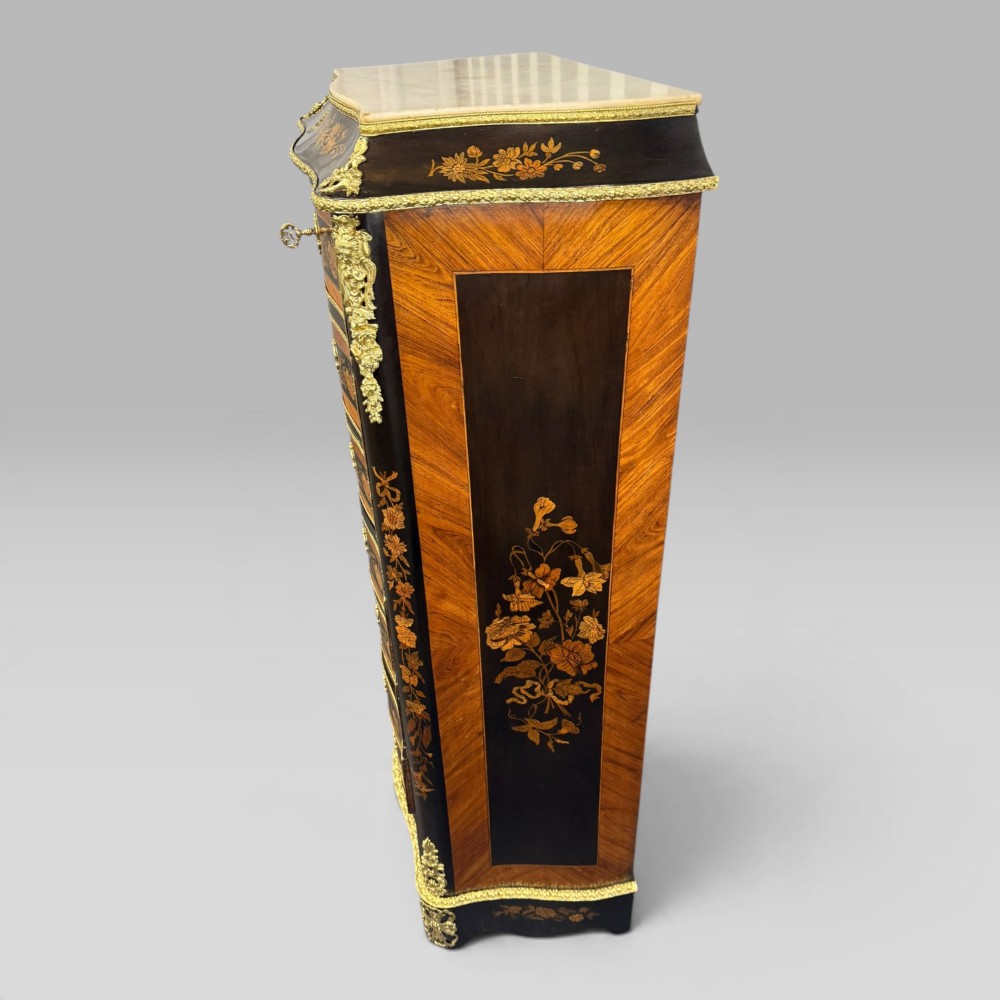 A pair of French Napoleon III narrow serpentine chests in kingwood and tulipwood featuring floral marquetry, gilt-bronze mounts, and marble tops. View V