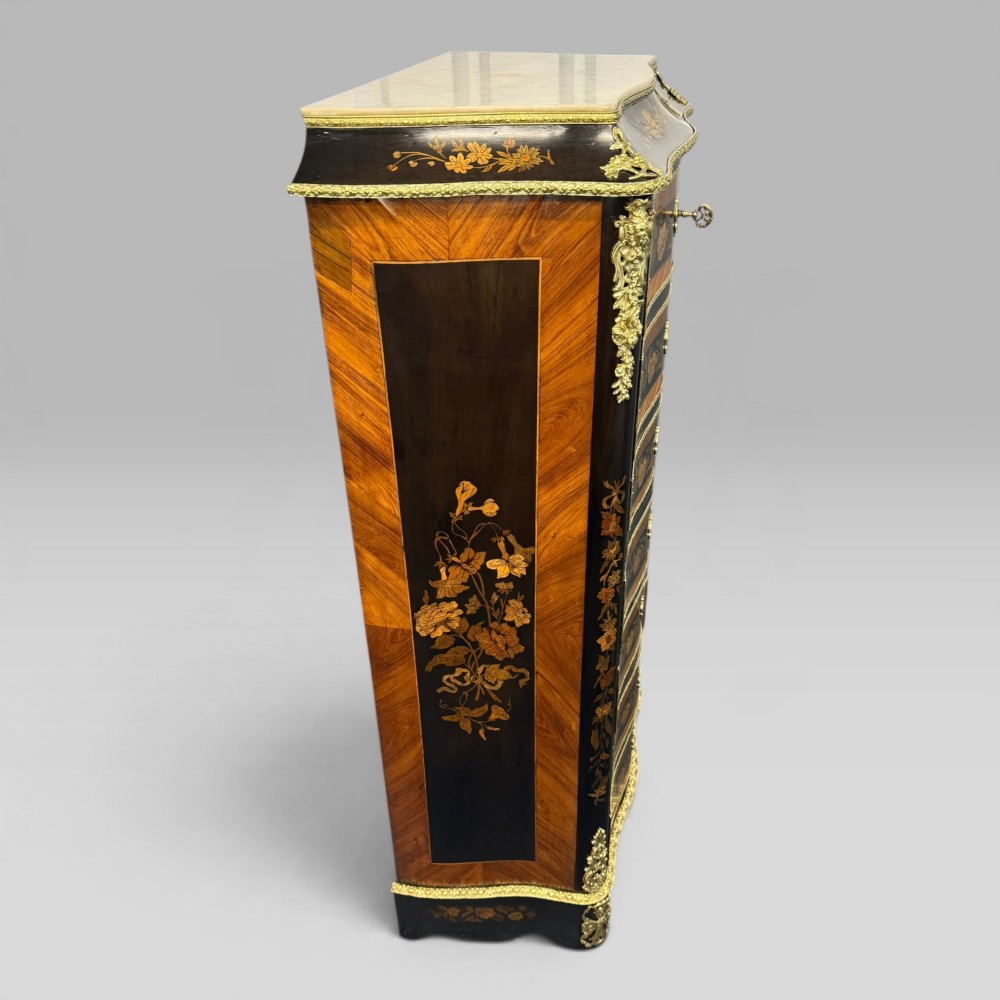 A pair of French Napoleon III narrow serpentine chests in kingwood and tulipwood featuring floral marquetry, gilt-bronze mounts, and marble tops. View VI
