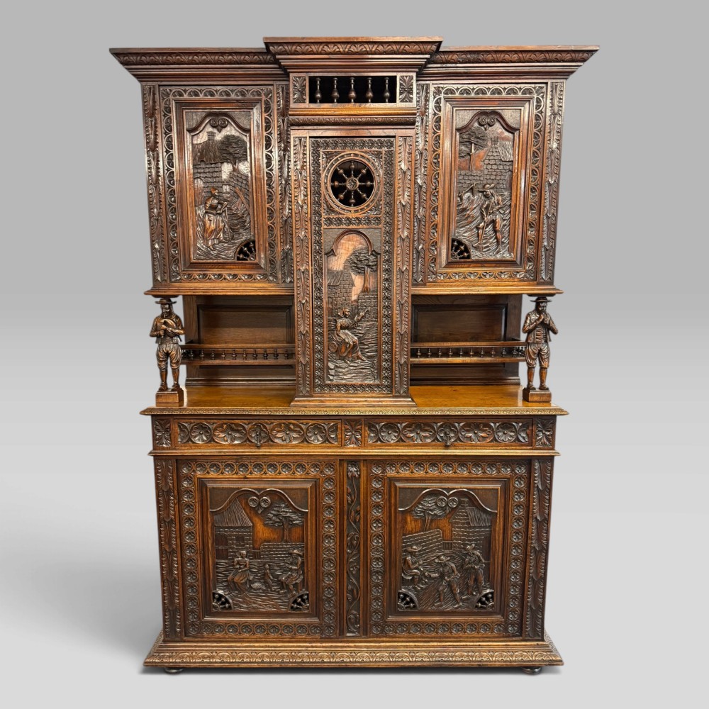 A mid-nineteenth-century dark oak French Breton buffet cabinet with detailed folk carvings, relief panels, ship wheel motifs, and carved human figure supports.