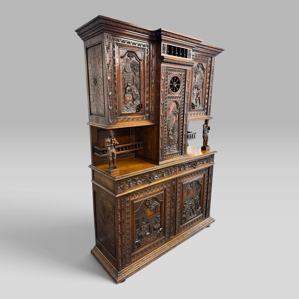 A mid-nineteenth-century dark oak French Breton buffet cabinet with detailed folk carvings, relief panels, ship wheel motifs, and carved human figure supports. View III