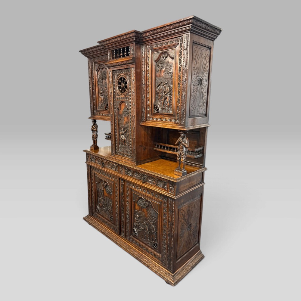 A mid-nineteenth-century dark oak French Breton buffet cabinet with detailed folk carvings, relief panels, ship wheel motifs, and carved human figure supports. View IV