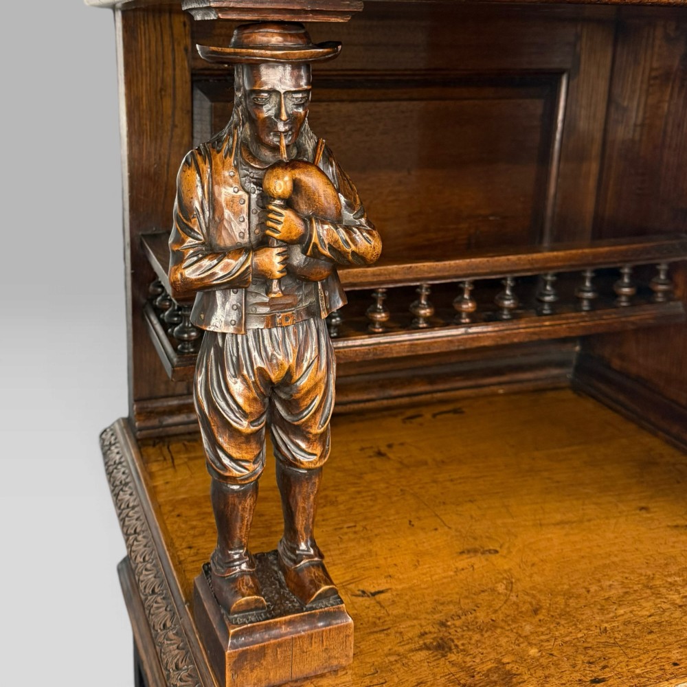 A mid-nineteenth-century dark oak French Breton buffet cabinet with detailed folk carvings, relief panels, ship wheel motifs, and carved human figure supports. View V