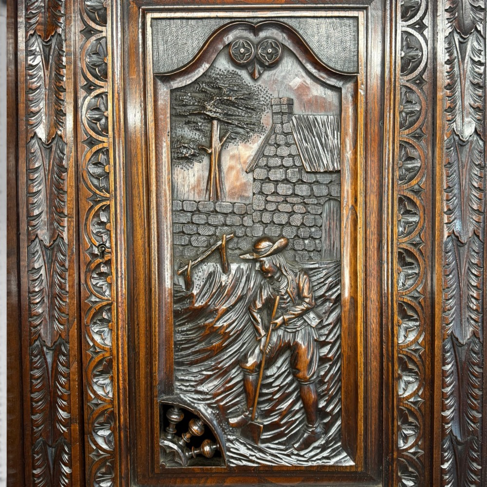 A mid-nineteenth-century dark oak French Breton buffet cabinet with detailed folk carvings, relief panels, ship wheel motifs, and carved human figure supports. View VII