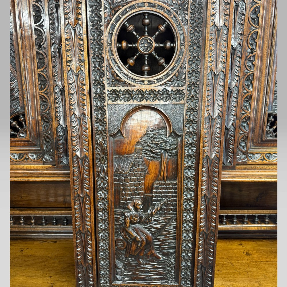 A mid-nineteenth-century dark oak French Breton buffet cabinet with detailed folk carvings, relief panels, ship wheel motifs, and carved human figure supports. View VIII