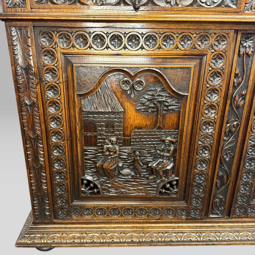 A mid-nineteenth-century dark oak French Breton buffet cabinet with detailed folk carvings, relief panels, ship wheel motifs, and carved human figure supports. View X